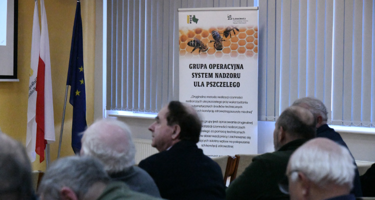 XXVIII Forum Pszczelarskie w Sielinku - System nadzoru ula pszczelego Na zdjęciu uczestnicy wydarzenia, w tle plakat informacyjny Grupy operacyjnej System nadzoru ula pszczelego.